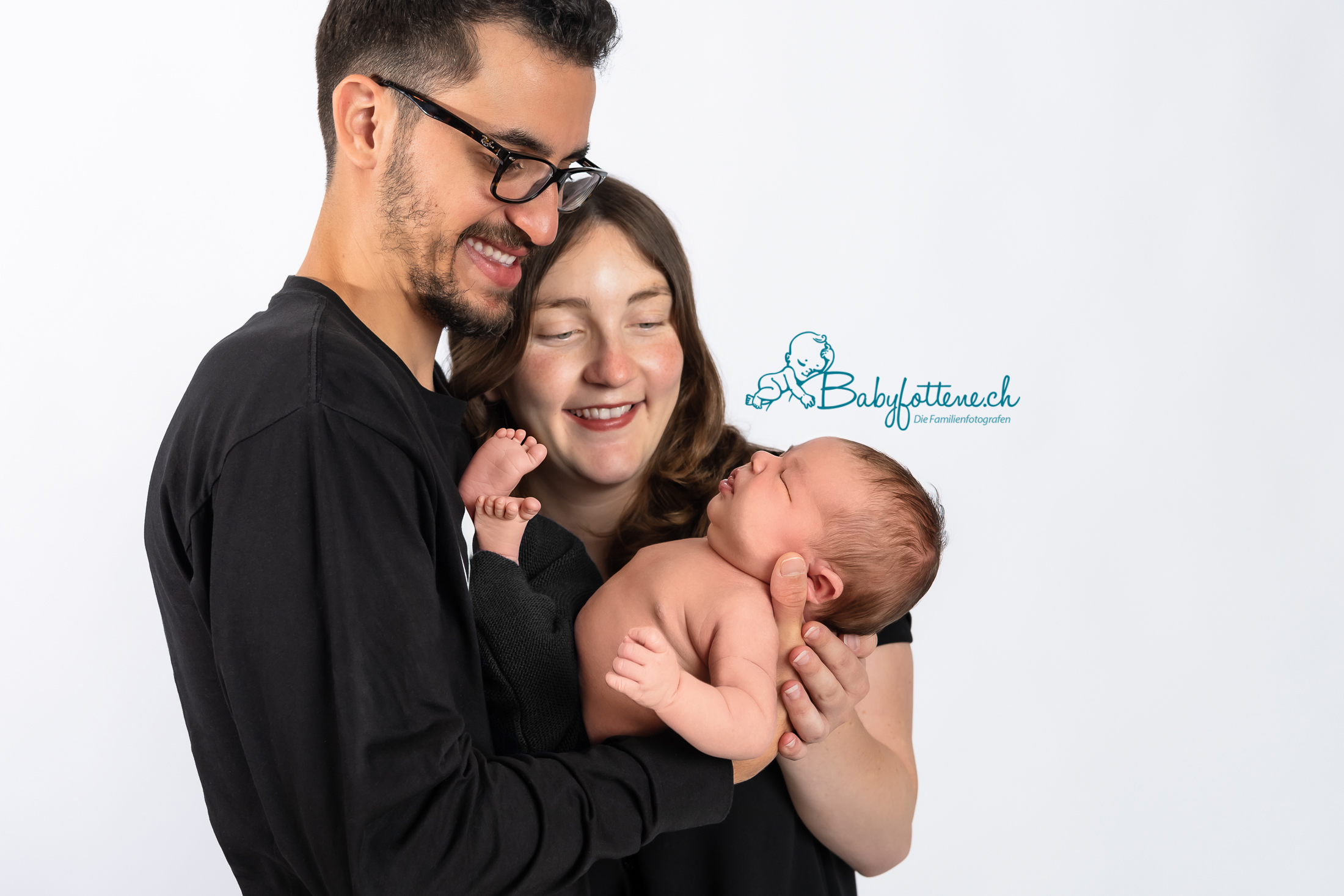 Frischgebackene Eltern schauen ihr Neugeborenes Baby beim Fotoshooting im Zürcher Oberland verliebt an